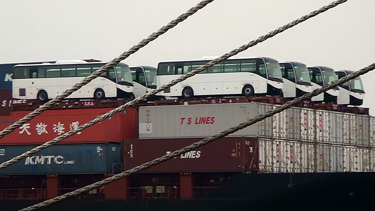 Buses on top of containers on a container ship, going down the Chao Phraya river